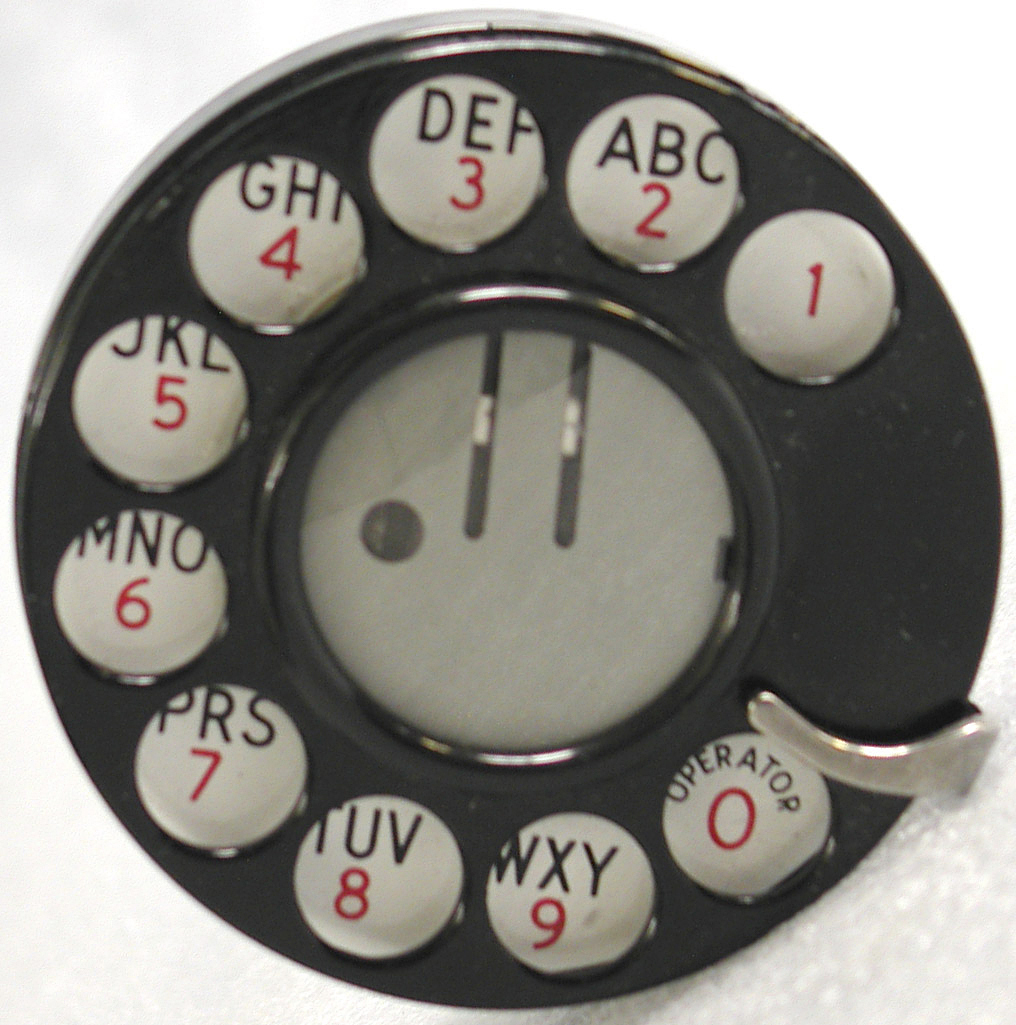 Rotary dial from a Western Electric telephone circa 1960 with holes around the perimeter showing numbers 1 through 9 corresponding to eight three-letter groups ABC through WXY (starting at 2) plus zero for the operator
